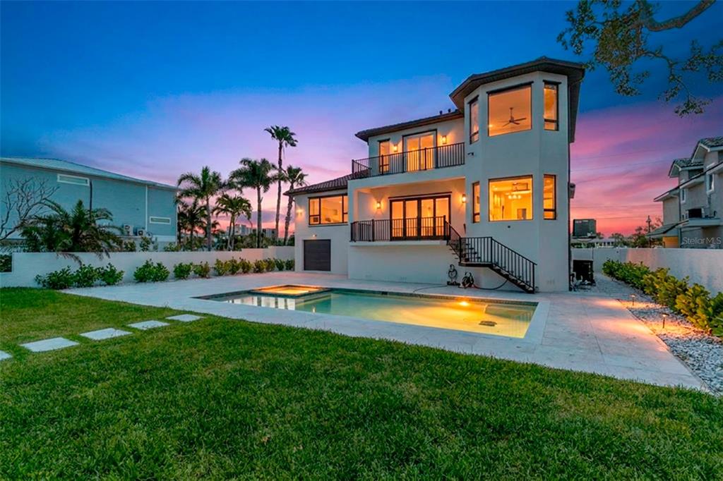 A multi-story house with a backyard pool, patio, and balcony at sunset — 4 PARADISE LANE, TREASURE ISLAND, FL