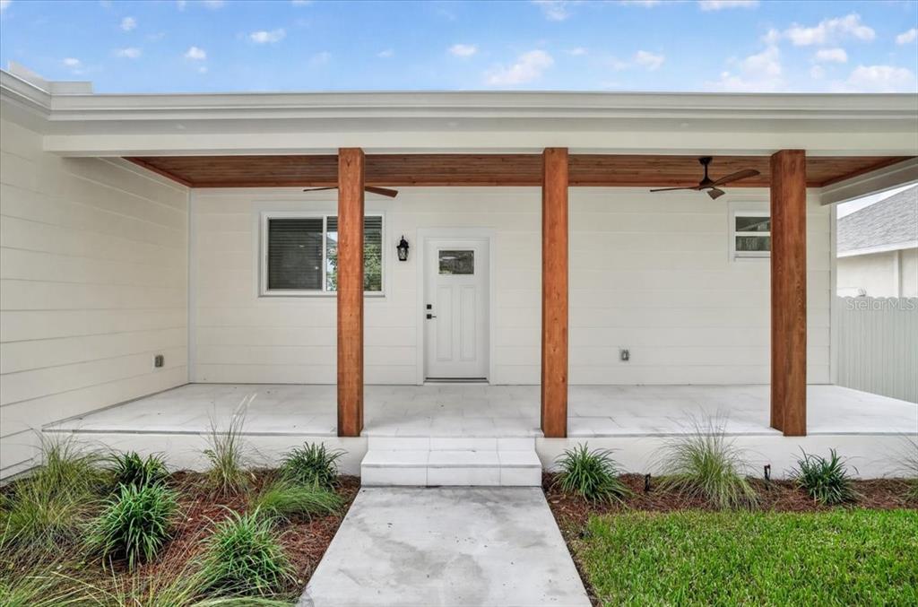A front porch with white siding, wooden support posts, and a wood-paneled ceiling — 412 17TH AVENUE W, PALMETTO, FL