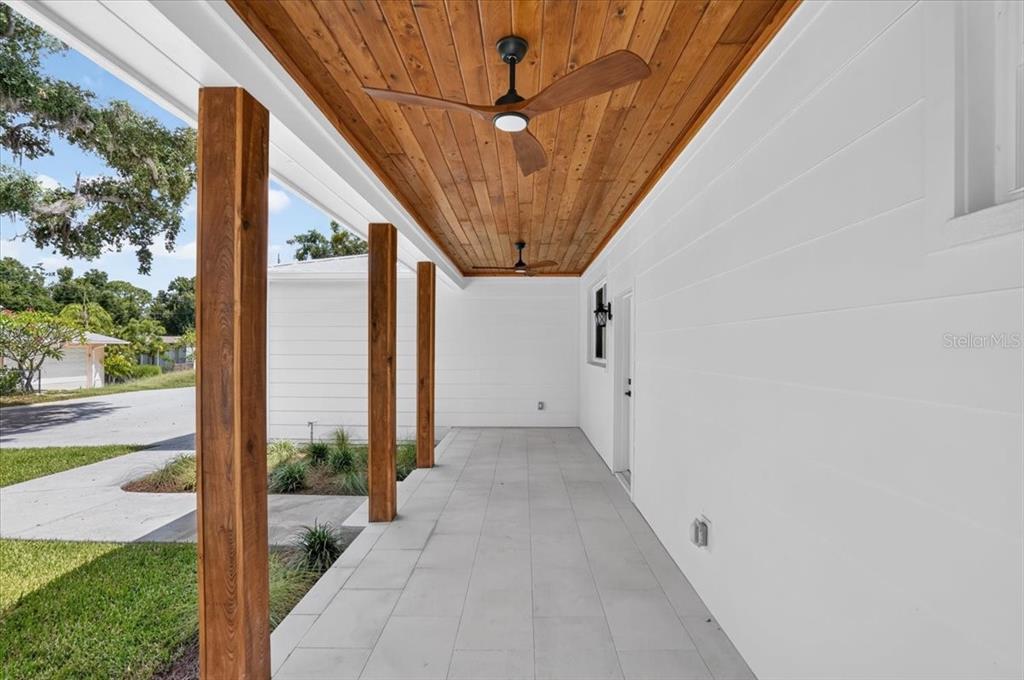 A covered porch features a wood-plank ceiling, ceiling fans, and square tile flooring — 412 17TH AVENUE W, PALMETTO, FL
