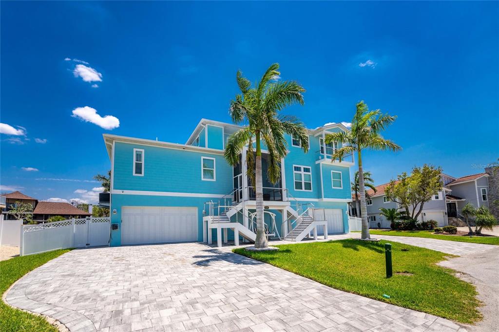 A bright blue multi-story house with a paved driveway and two palm trees — 9290 PINE COVE DRIVE, ENGLEWOOD, FL