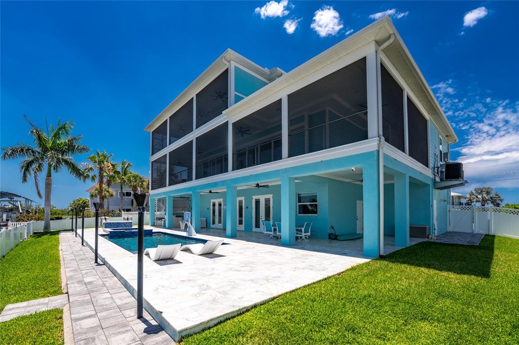 The exterior of a two-story house features a screened-in porch, pool, and patio area — 9290 PINE COVE DRIVE, ENGLEWOOD, FL