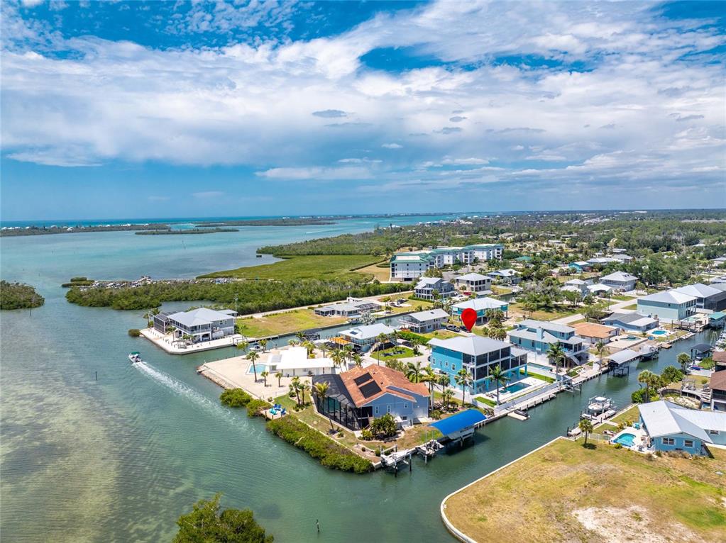 An aerial view shows a multi-story house with a red marker on a waterfront lot — 9290 PINE COVE DRIVE, ENGLEWOOD, FL