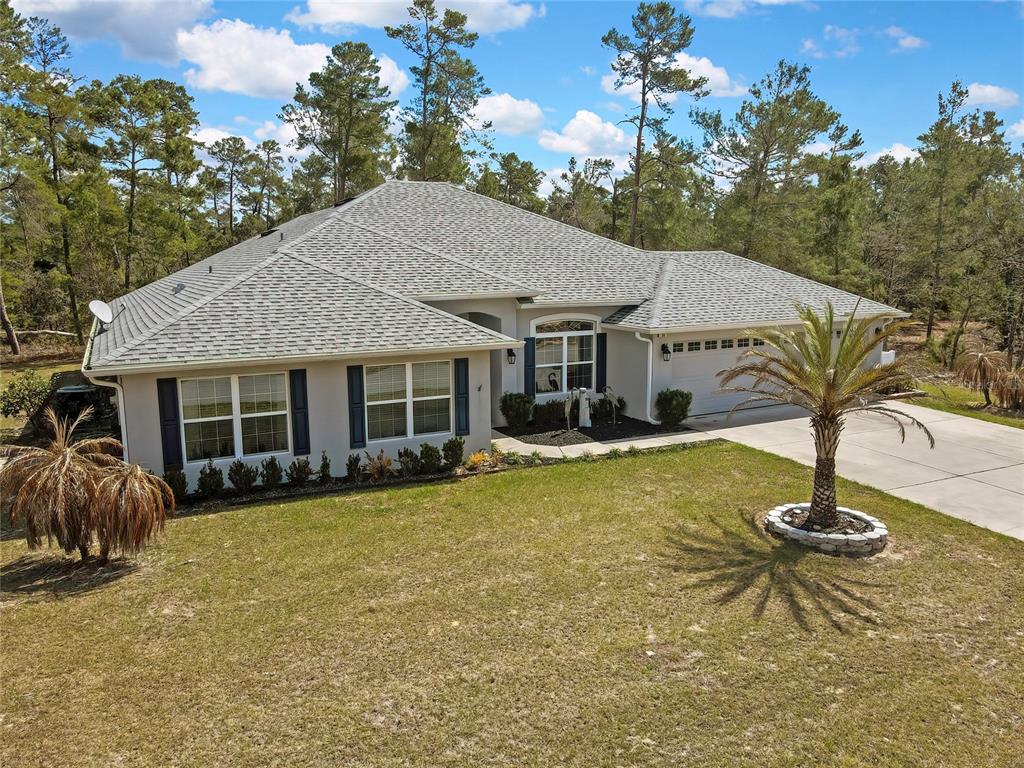 A single-story house with a gray roof, light-colored stucco walls, and a front lawn — 24 TALL MARIGOLDS COURT, HOMOSASSA, FL