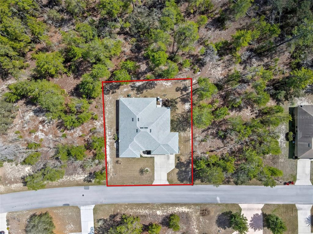 An aerial view shows a house with a gray roof situated on a wooded lot — 24 TALL MARIGOLDS COURT, HOMOSASSA, FL