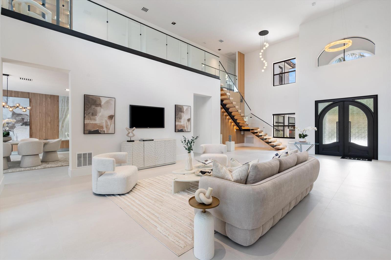 A bright, modern living room features a floating staircase, high ceilings, and neutral-toned furniture — 17585 Middlebrook Way, Boca Raton FL 33496, BOCA RATON, FL