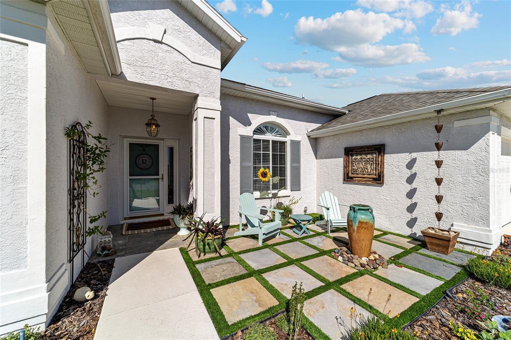 A front patio features stone pavers with artificial turf, two chairs, and a decorative fountain — 2380 NW 55TH AVENUE ROAD, OCALA, FL