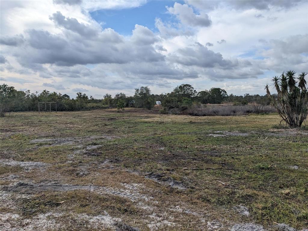 A wide, grassy, and partially cleared vacant lot under a cloudy sky — 4830 HOLOPAW STREET, LAKE WALES, FL