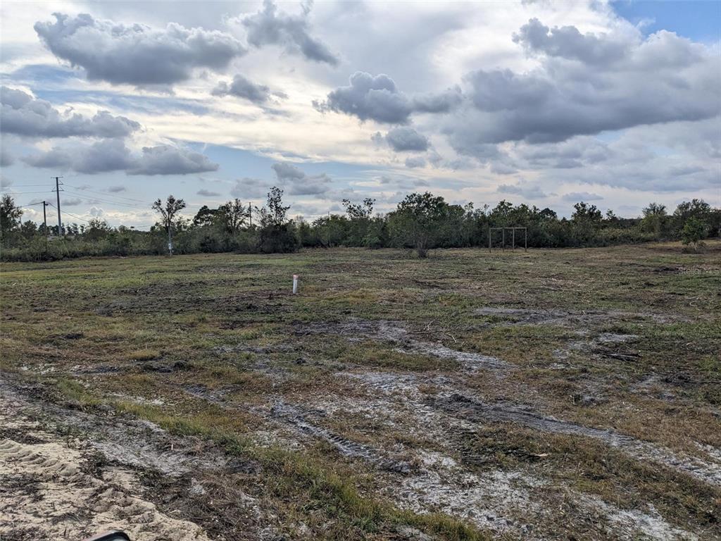 A flat, cleared, grassy lot under a cloudy sky with a single utility pipe visible — 4830 HOLOPAW STREET, LAKE WALES, FL