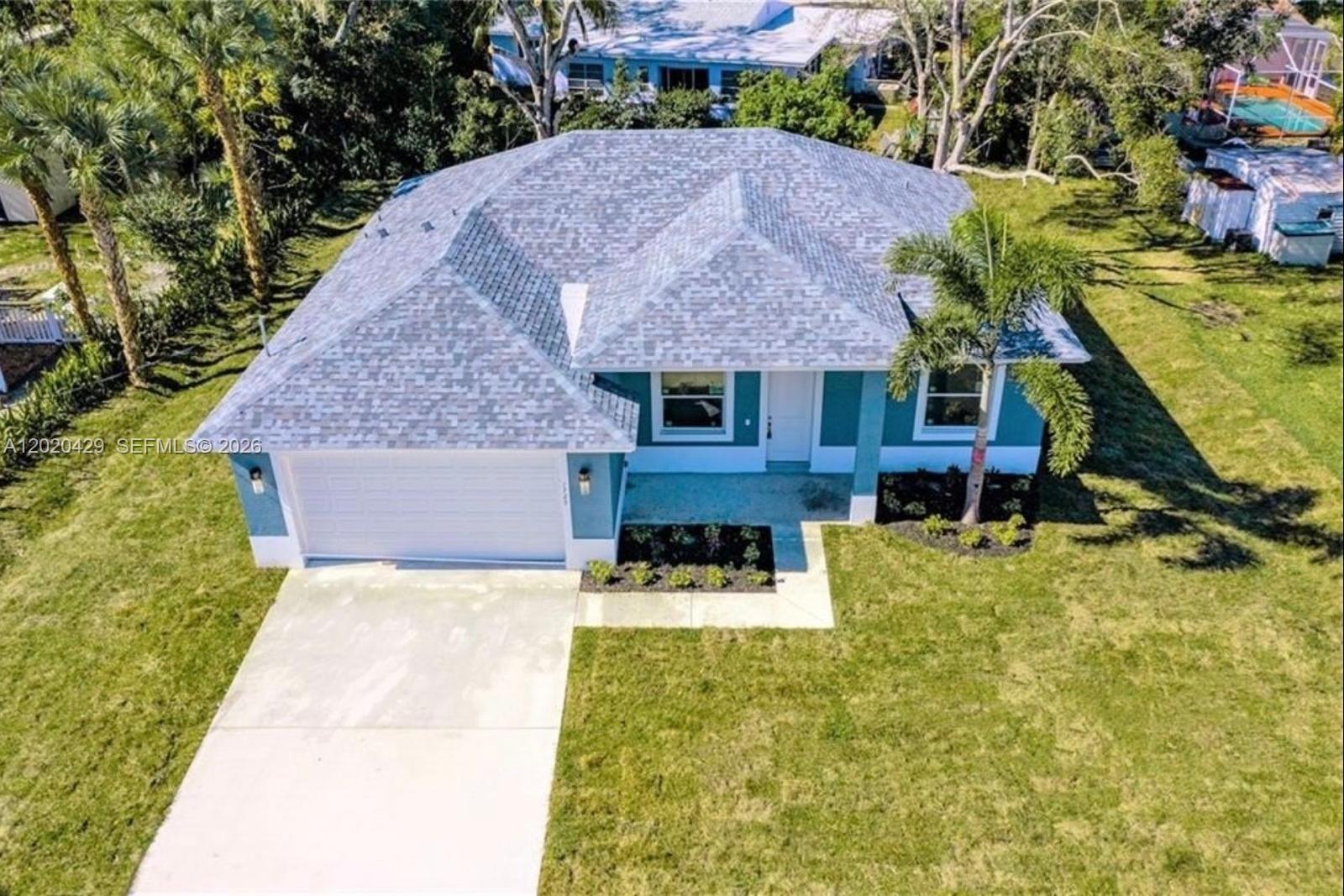 An aerial view of a single-story teal house with a gray shingled roof and driveway — 1725 20th Ave, Vero Beach FL 32960, VERO BEACH, FL