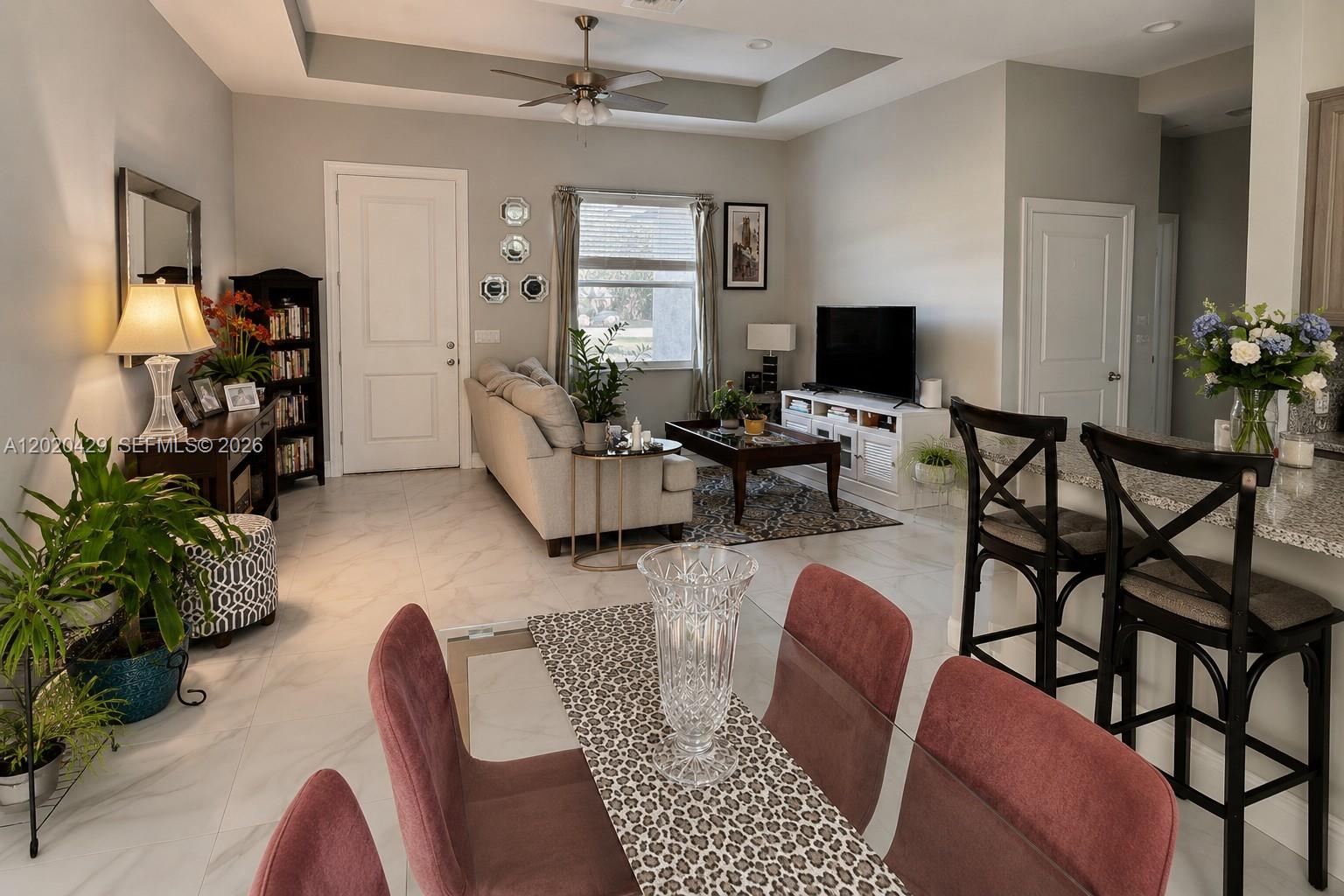 An open-concept living and dining area features tile flooring, a tray ceiling, and neutral walls — 1725 20th Ave, Vero Beach FL 32960, VERO BEACH, FL