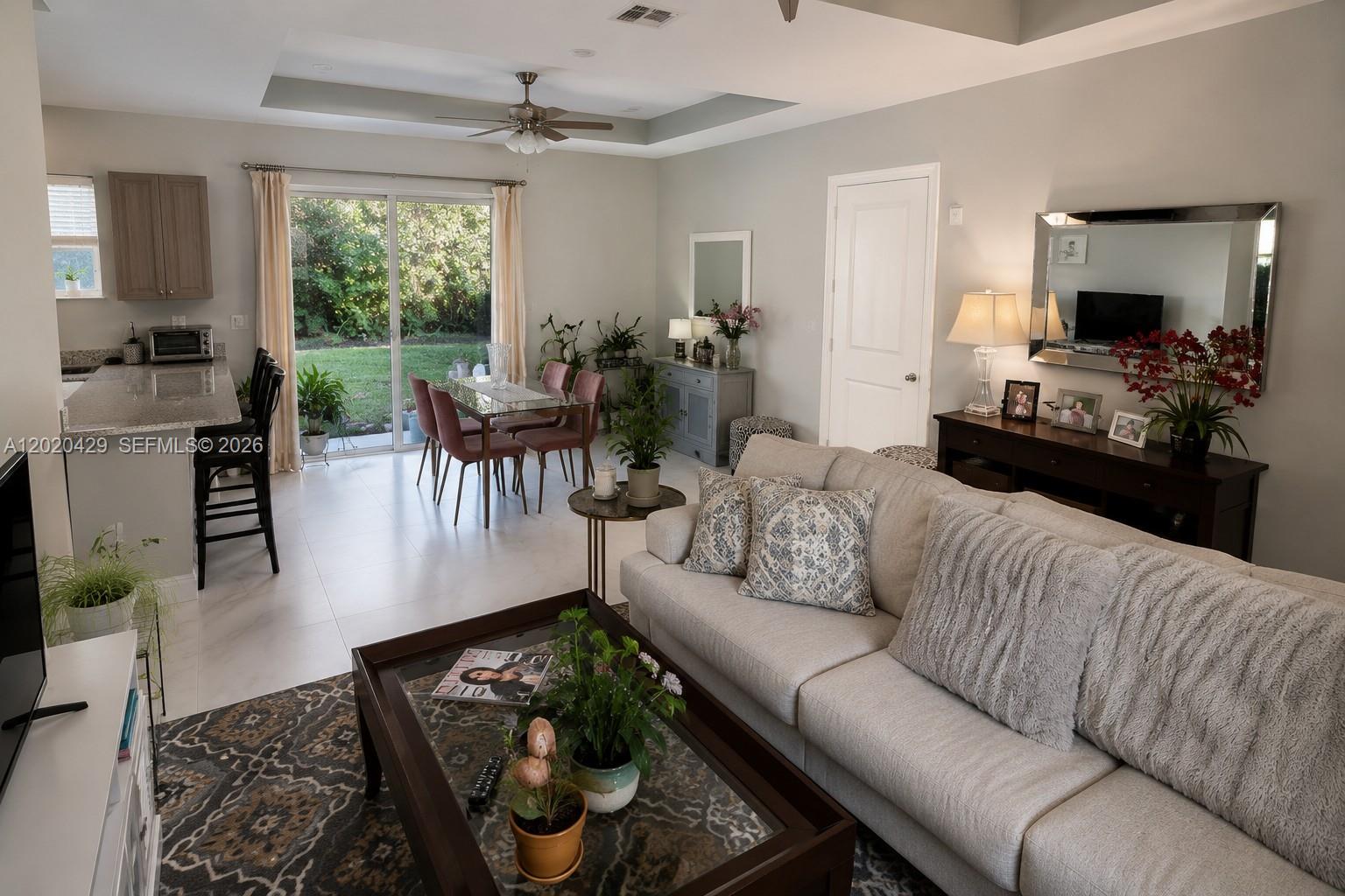 An open-concept living and dining area features tile flooring, a neutral sofa, and sliding glass doors — 1725 20th Ave, Vero Beach FL 32960, VERO BEACH, FL