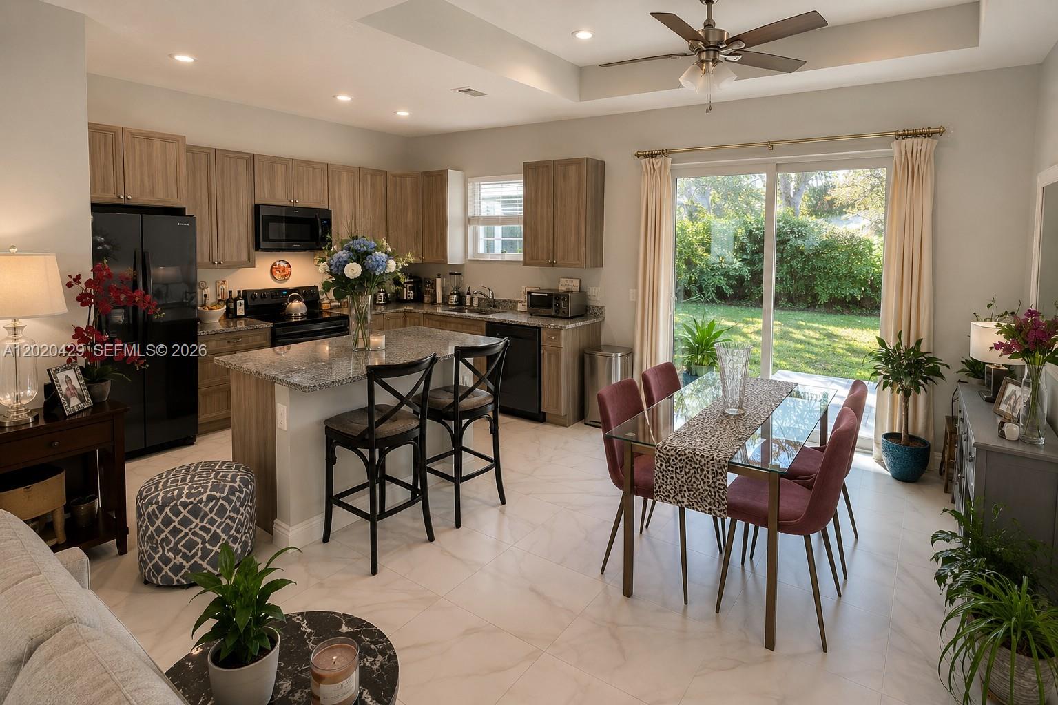 A kitchen with wood cabinets and granite countertops opens to a dining area with glass doors — 1725 20th Ave, Vero Beach FL 32960, VERO BEACH, FL
