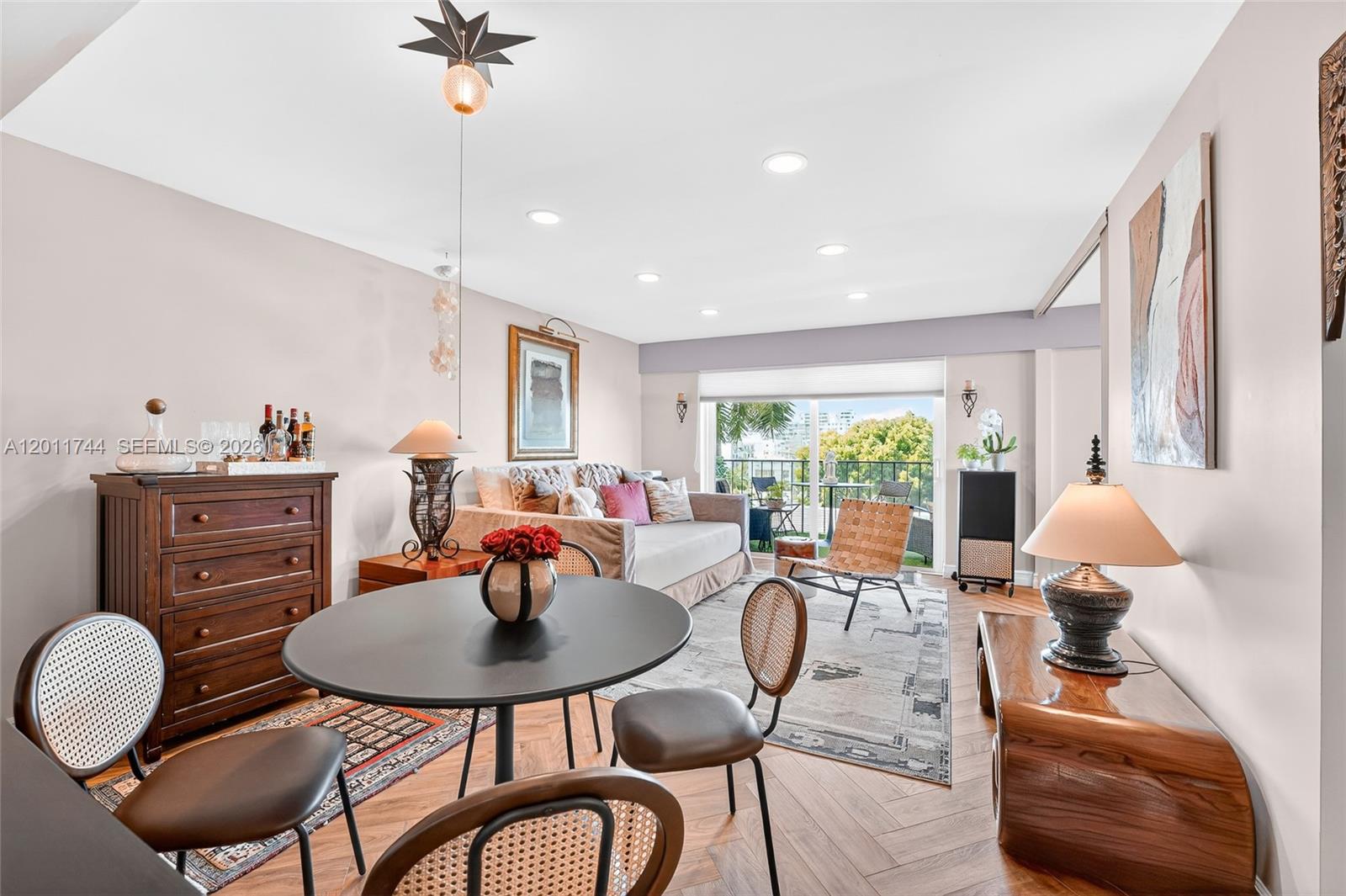 A living and dining area features herringbone wood floors, a round table, and a balcony — 1455 West Ave # 501, Miami Beach FL 33139, MIAMI BEACH, FL
