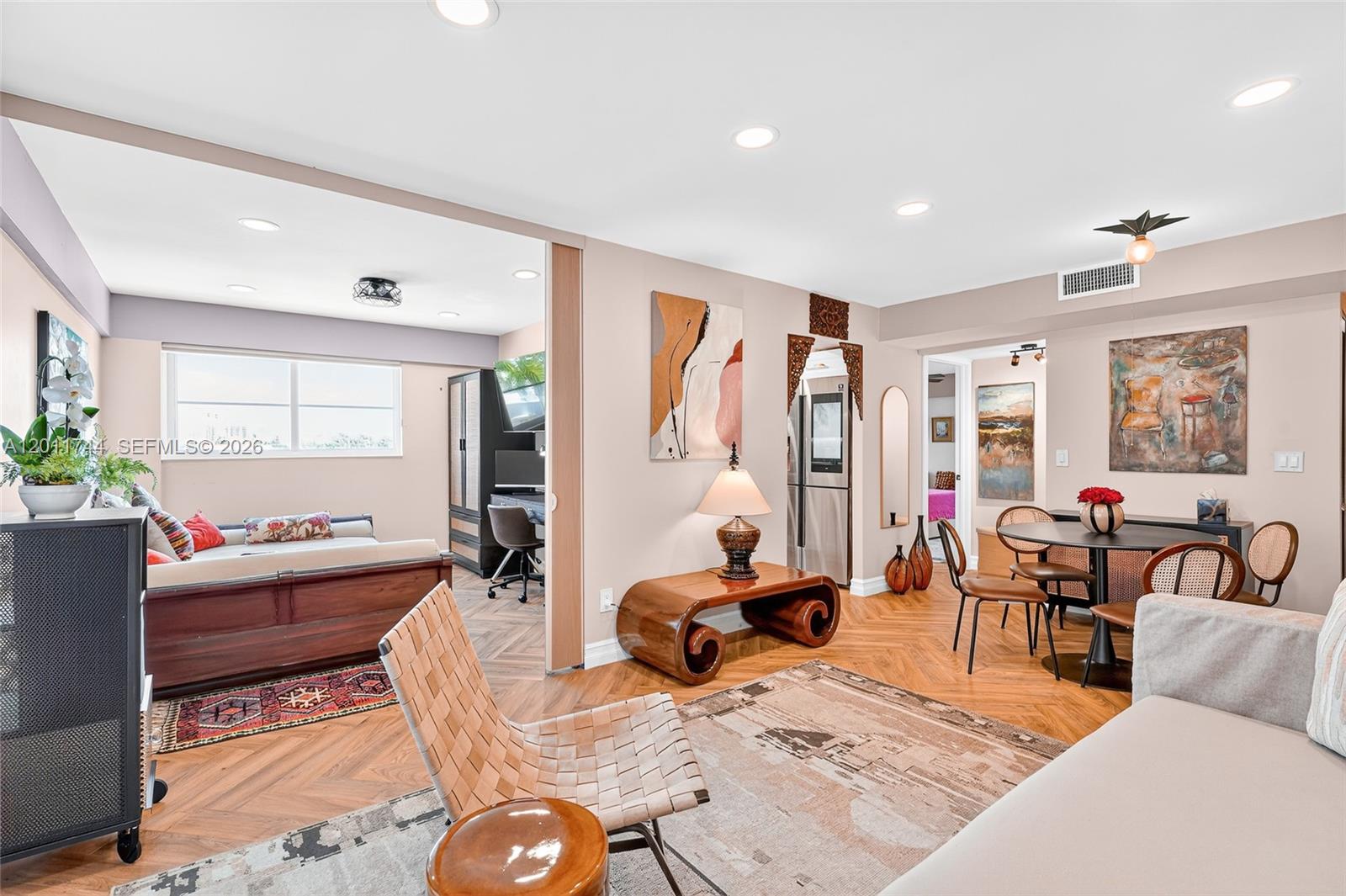 An open-concept living and dining area features herringbone wood floors and a separate office space — 1455 West Ave # 501, Miami Beach FL 33139, MIAMI BEACH, FL