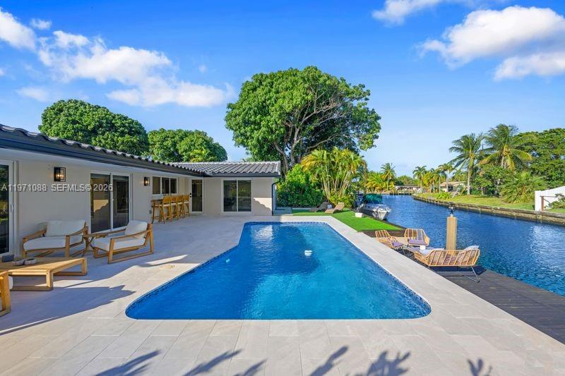 A swimming pool sits on a patio next to a house along a canal — 1810 SW 6th Ave, Pompano Beach FL 33060, POMPANO BEACH, FL