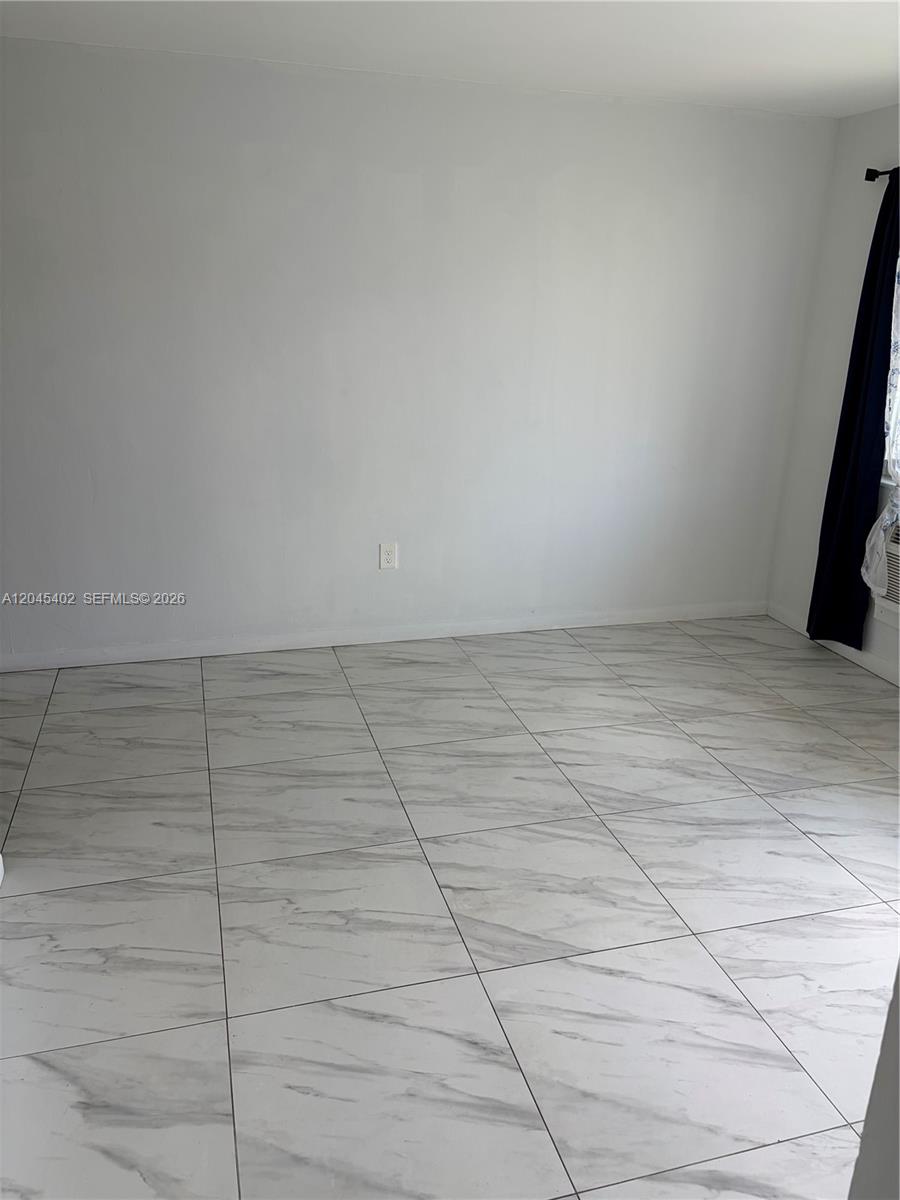 An empty room features white walls, a single electrical outlet, and white marble-patterned tile flooring — 14399 NE 5th Pl # 5, North Miami FL 33161, NORTH MIAMI, FL