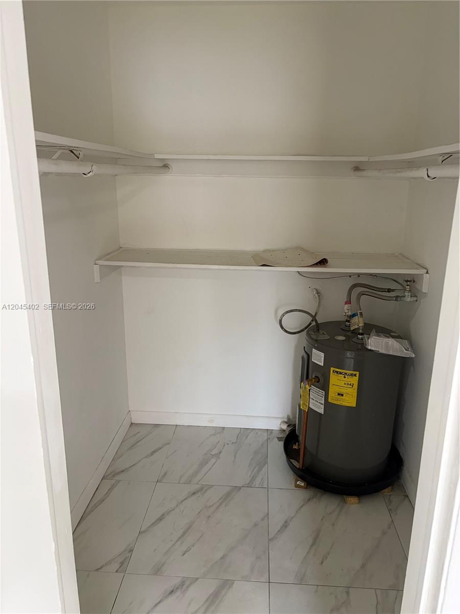 A closet contains a water heater, white shelving, and light-colored marble-style tile flooring — 14399 NE 5th Pl # 5, North Miami FL 33161, NORTH MIAMI, FL