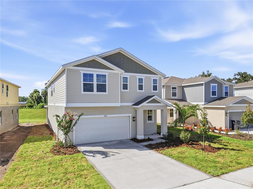 A two-story suburban house with beige siding, a white garage door, and a concrete driveway — 2513 29TH LANE E, PALMETTO, FL