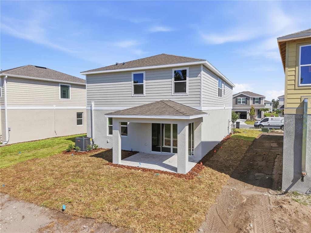 The rear exterior of a two-story house features a covered patio and a small yard — 2513 29TH LANE E, PALMETTO, FL