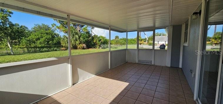 A screened-in porch with tiled flooring, white aluminum framing, and a view of a grassy yard — 7855 W PRICE BOULEVARD, NORTH PORT, FL