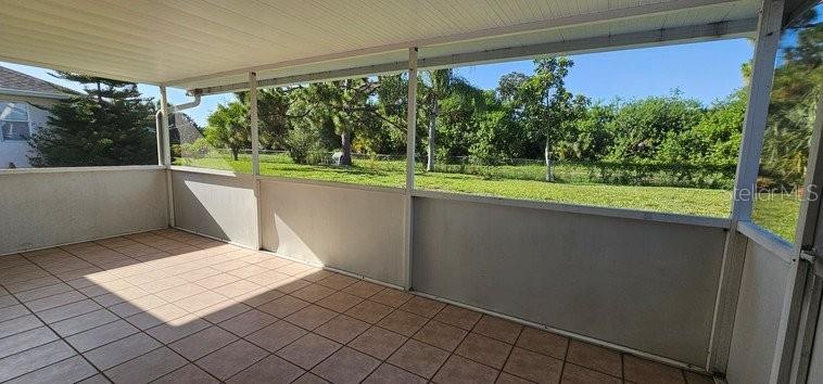 A tiled, screened-in porch overlooks a grassy backyard with trees — 7855 W PRICE BOULEVARD, NORTH PORT, FL