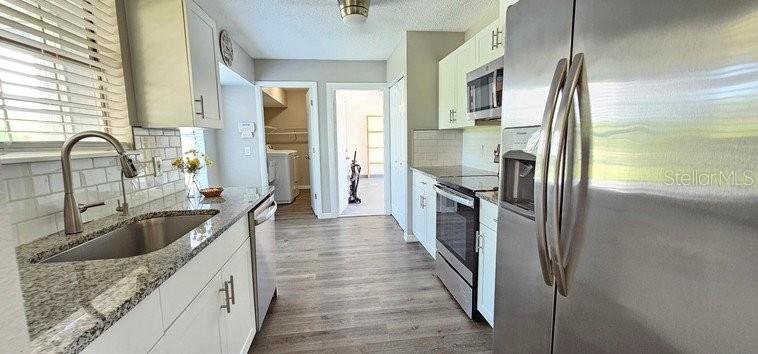 A kitchen with white cabinets, granite countertops, stainless steel appliances, and wood-look flooring — 7855 W PRICE BOULEVARD, NORTH PORT, FL