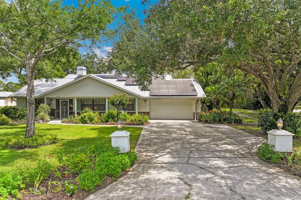 A single-story house with a metal roof, solar panels, and a concrete driveway — 7565 CASTLE DRIVE, SARASOTA, FL