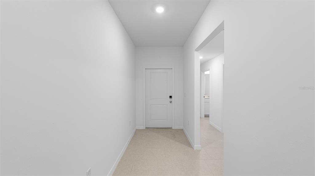 A bright, empty entryway with white walls, tile flooring, and a single white door — 1629 DORCHESTER STREET, PORT CHARLOTTE, FL