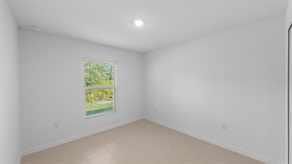 An empty bedroom features white walls, light-colored tile flooring, and a single window with blinds — 1629 DORCHESTER STREET, PORT CHARLOTTE, FL