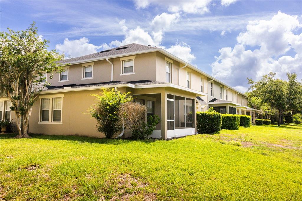 The exterior of a two-story townhouse features a screened-in back porch and a grassy yard — 5428 CARAMELLA DRIVE, ORLANDO, FL