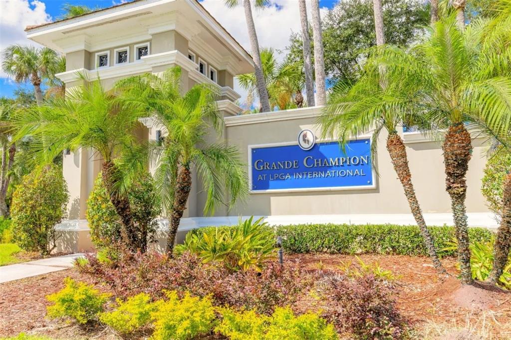 A blue sign for Grande Champion at LPGA International stands before a beige entrance structure — 106 CARMICHAEL WAY, DAYTONA BEACH, FL