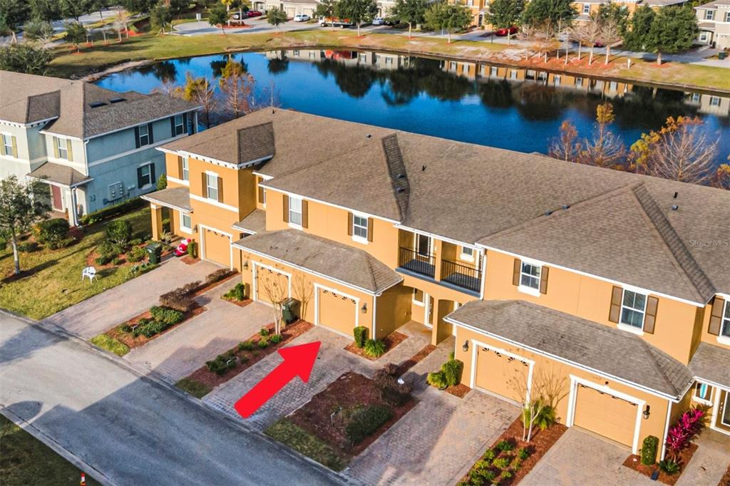 An aerial view of a tan townhouse complex with a red arrow pointing to a garage — 106 CARMICHAEL WAY, DAYTONA BEACH, FL