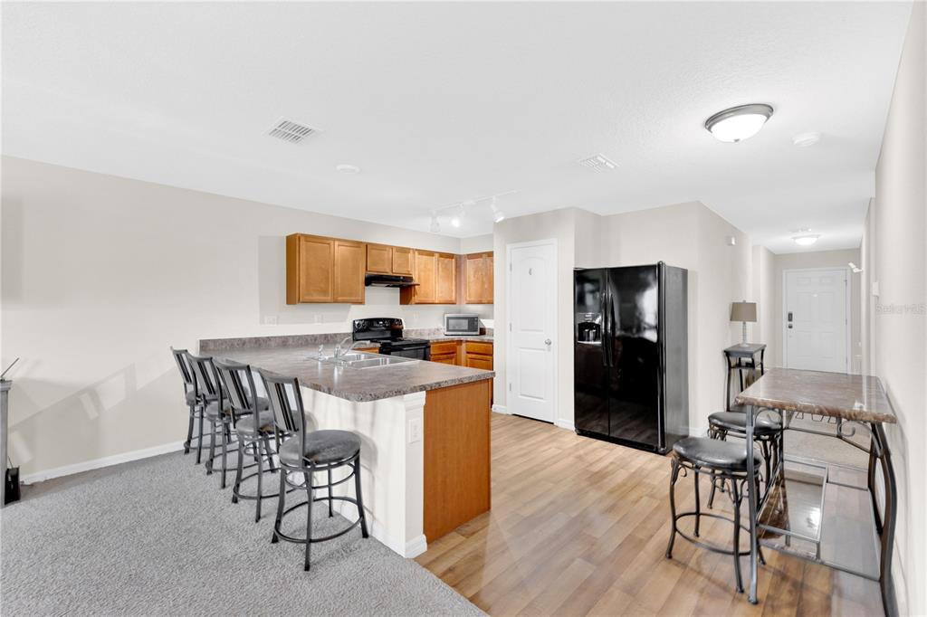 A kitchen with wood cabinets, a breakfast bar with stools, and a dining area — 113 TULIP LANE, KISSIMMEE, FL