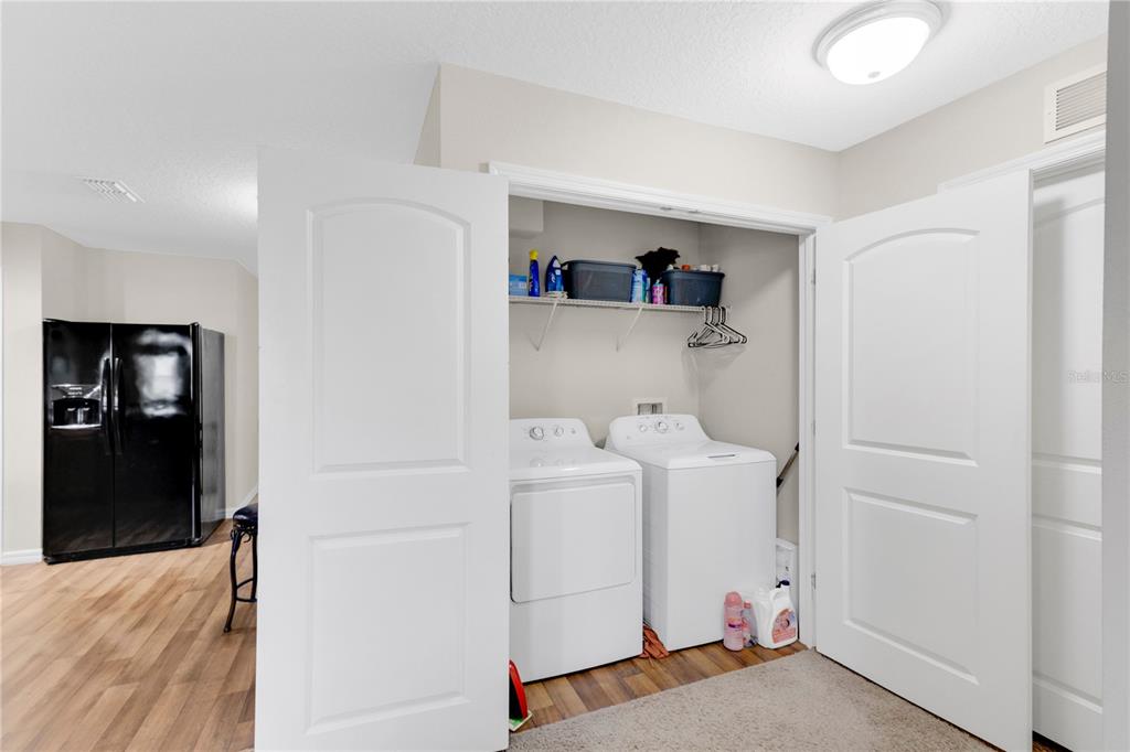 A laundry closet with a washer and dryer sits in a room with wood flooring — 113 TULIP LANE, KISSIMMEE, FL