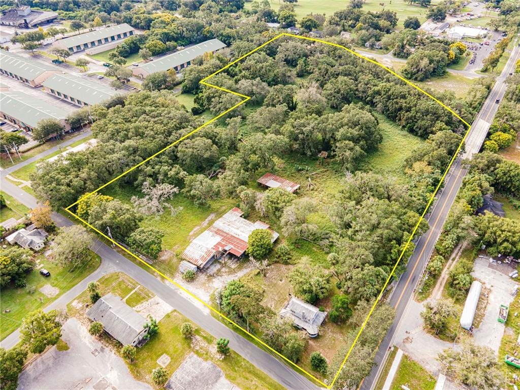 An aerial view shows a large, wooded lot with two structures and a metal roof — 610 S HIGHLAND STREET, MOUNT DORA, FL