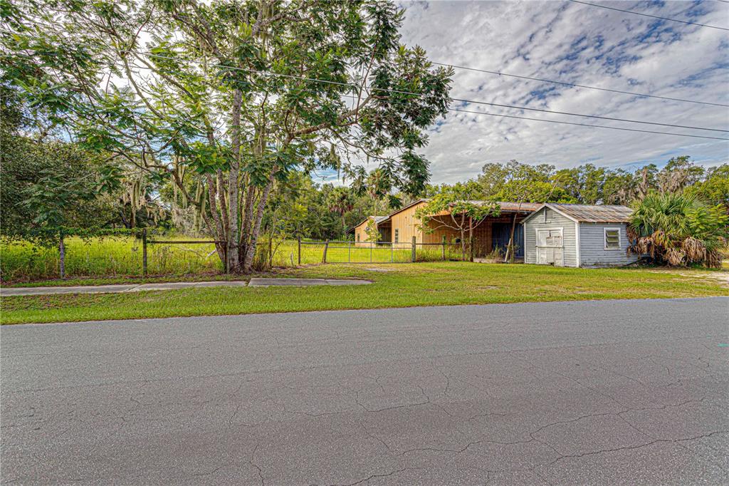 A gravel driveway leads to a small shed and a barn behind a wire fence — 610 S HIGHLAND STREET, MOUNT DORA, FL