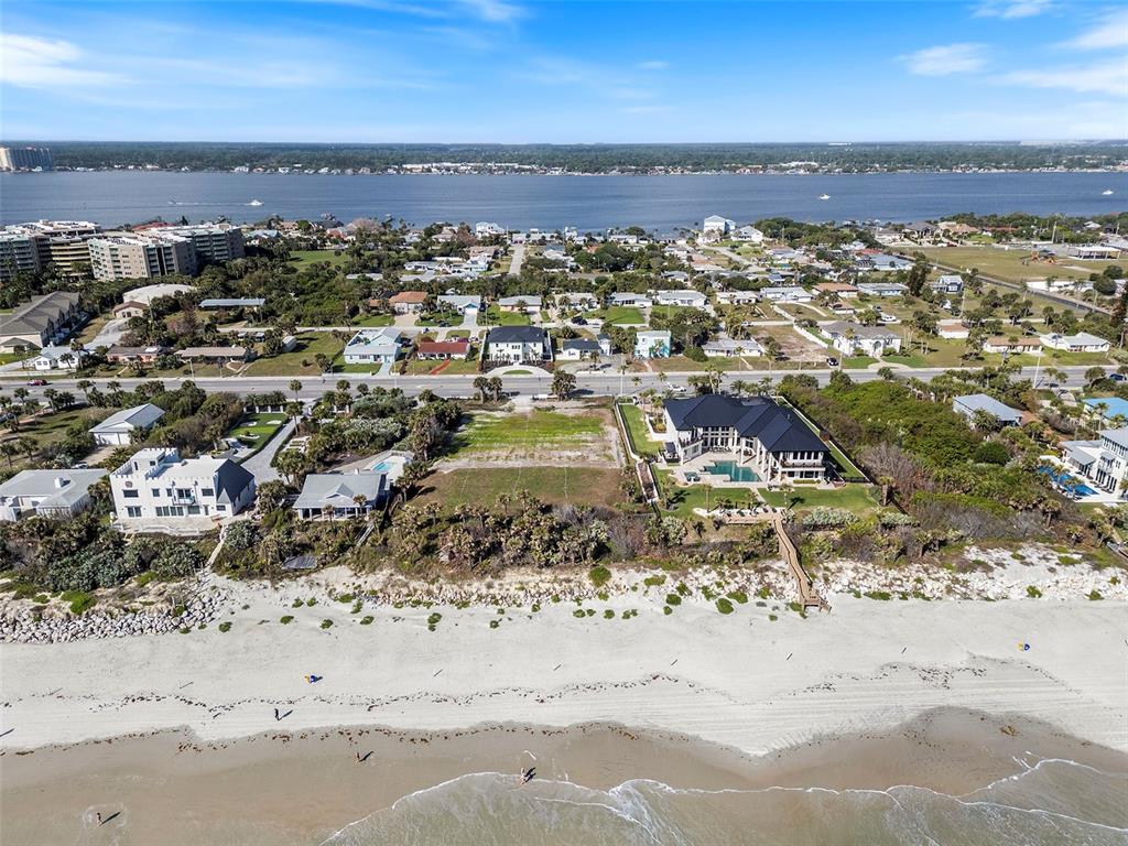 An aerial view shows a beachfront property with a large house, pool, and vacant lot — 2825 S ATLANTIC AVENUE, DAYTONA BEACH, FL