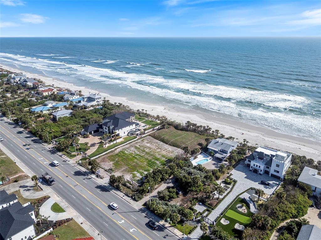 An aerial view shows beachfront homes, a vacant lot, and a road along the coast — 2825 S ATLANTIC AVENUE, DAYTONA BEACH, FL