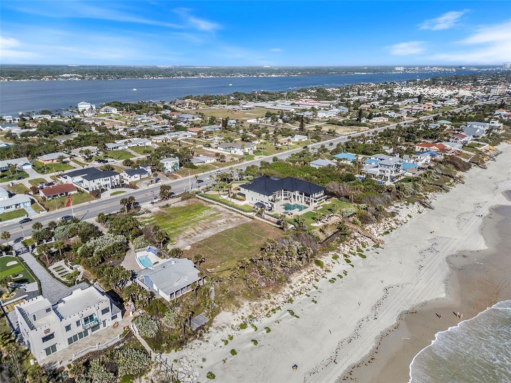 An aerial view shows a coastal neighborhood with a large house featuring a dark roof — 2825 S ATLANTIC AVENUE, DAYTONA BEACH, FL