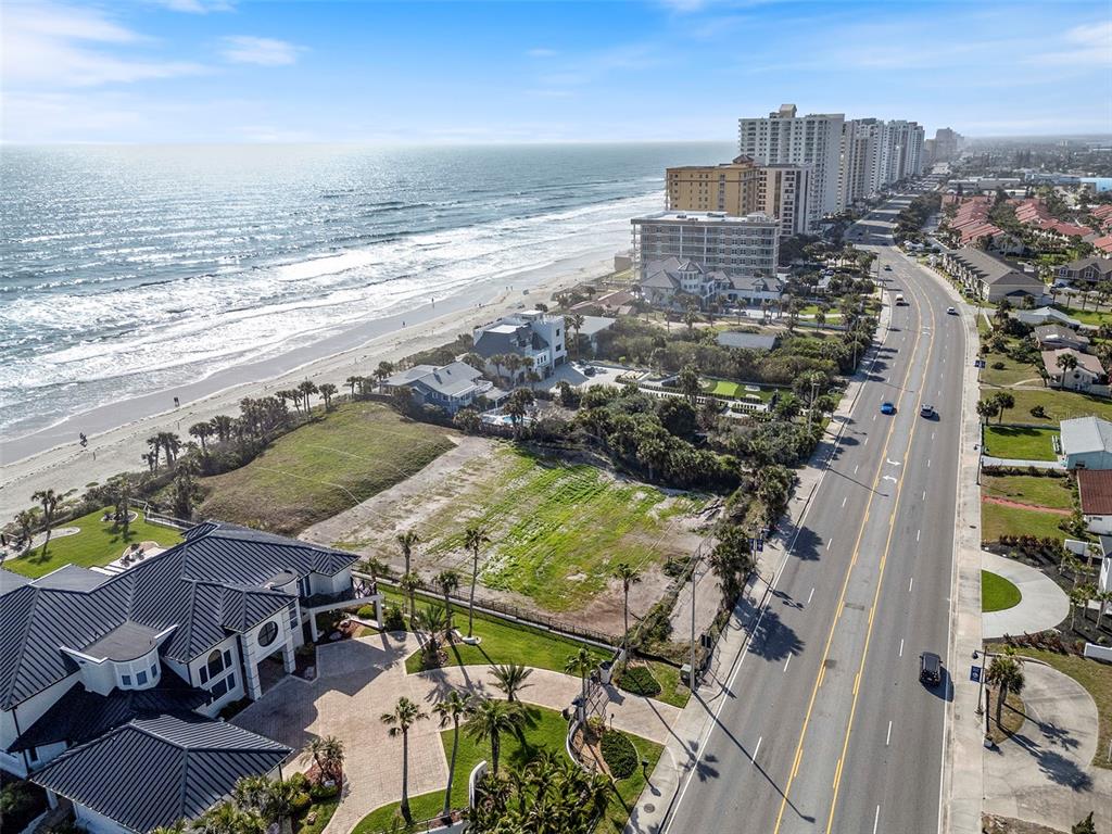 An aerial view shows a vacant beachfront lot situated between a large house and a road — 2825 S ATLANTIC AVENUE, DAYTONA BEACH, FL