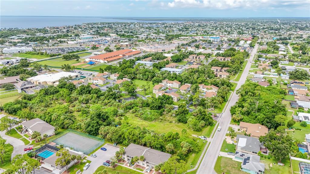 Aerial view of a residential neighborhood with apartment buildings, a tennis court, and surrounding vegetation — 22501 WESTCHESTER BOULEVARD, PUNTA GORDA, FL