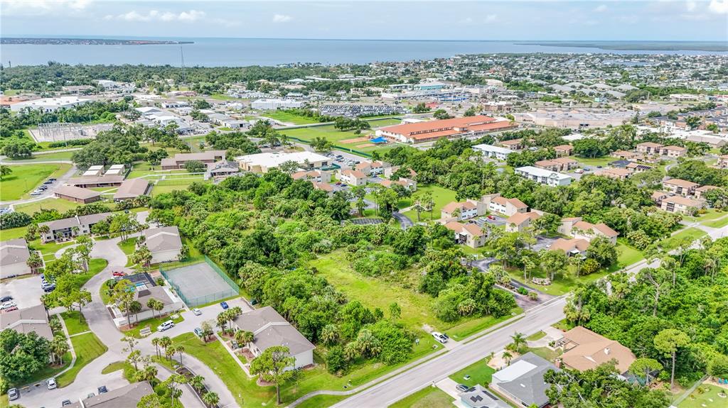 This aerial view shows a residential apartment complex surrounded by trees and nearby commercial buildings — 22501 WESTCHESTER BOULEVARD, PUNTA GORDA, FL