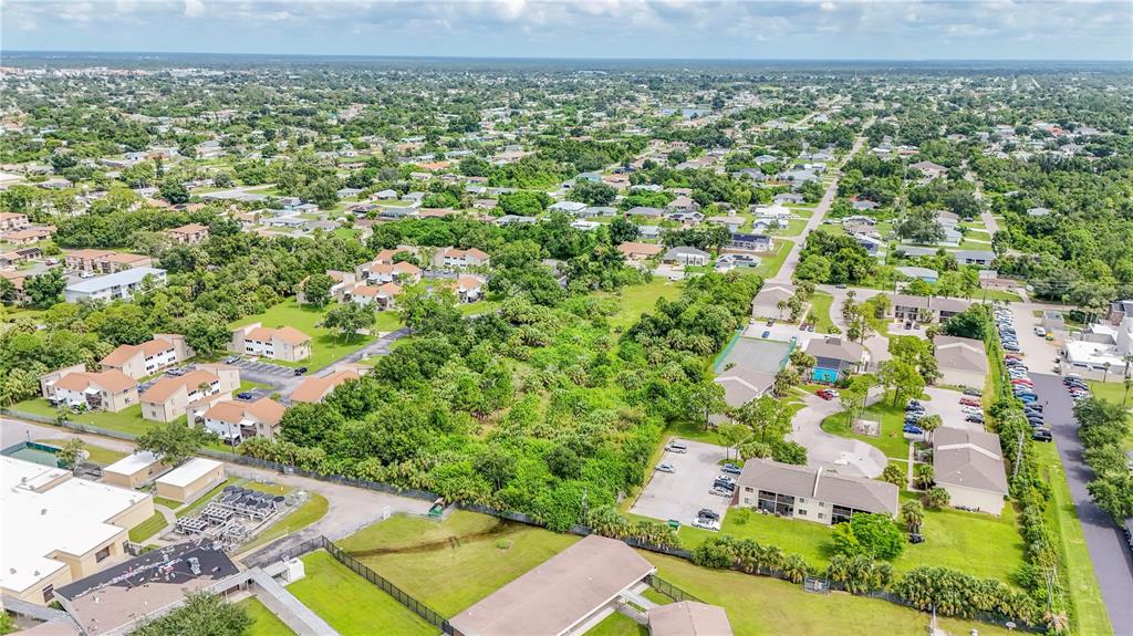 An aerial view shows multiple apartment buildings surrounded by dense trees and paved parking lots — 22501 WESTCHESTER BOULEVARD, PUNTA GORDA, FL