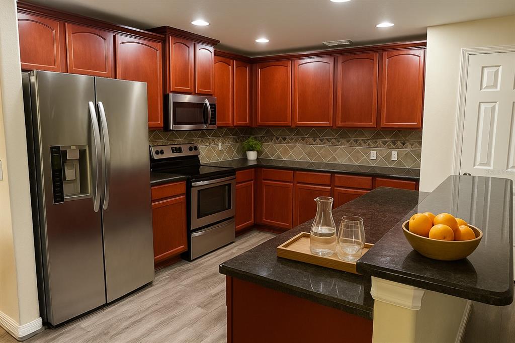 A kitchen features cherry wood cabinets, stainless steel appliances, and a dark granite breakfast bar — 2924 BOATING BOULEVARD, KISSIMMEE, FL