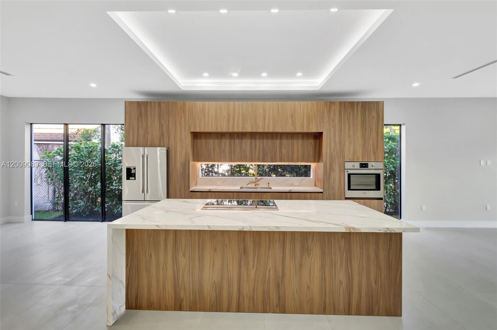 A modern kitchen features wood cabinetry, a marble waterfall island, and a recessed ceiling light — 1223 SW 12th Ct # 1223, Miami FL 33135, MIAMI, FL