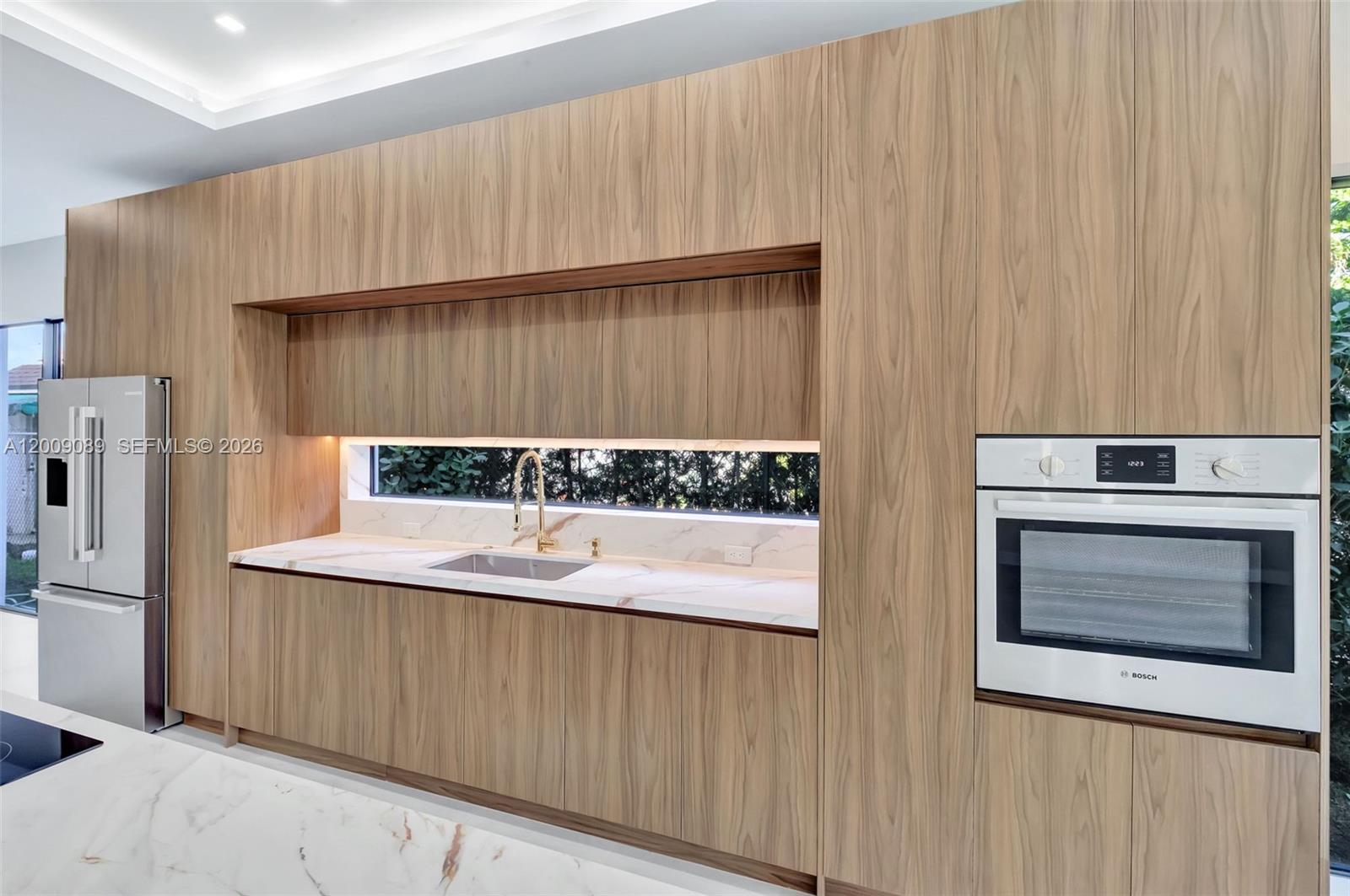 A modern kitchen features wood-grain cabinetry, white marble countertops, and a built-in Bosch oven — 1223 SW 12th Ct # 1223, Miami FL 33135, MIAMI, FL