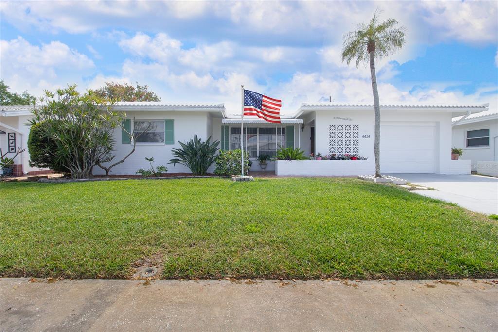 A single-story white house with a lawn, an American flag, and a palm tree — 4434 100TH AVENUE N, PINELLAS PARK, FL