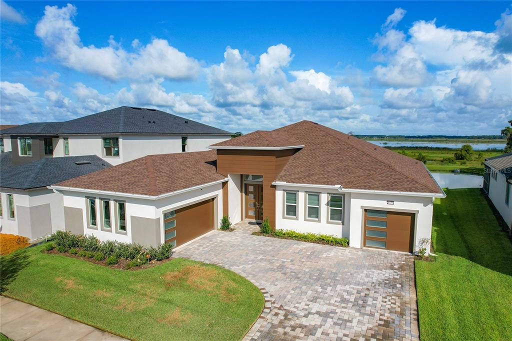 An exterior view of a modern single-story house with a paved driveway and attached garages — 8859 IVY STARK BOULEVARD, WESLEY CHAPEL, FL