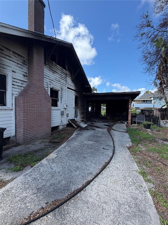 The exterior of a house shows fire damage to the siding and an attached carport — 512 E HICKORY STREET, ARCADIA, FL