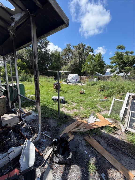 A view from a fire-damaged porch looking out toward a grassy backyard — 512 E HICKORY STREET, ARCADIA, FL